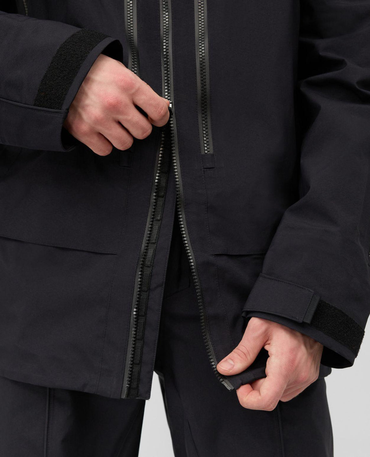 Närbild på Mammut Eiger Free Pro HS Hooded Jacket i svart, där dragkedjan dras upp.