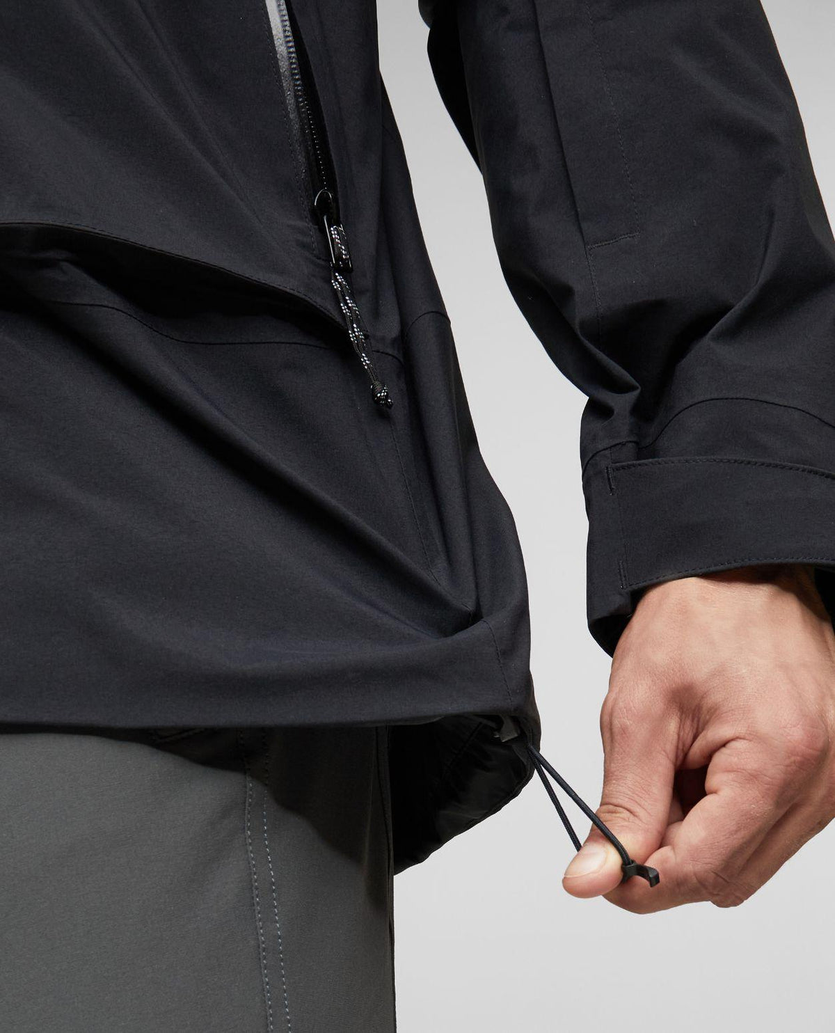 Närbild på justering av midjan på svarta Mammut Haldigrat Gore-Tex HS Thermo Hooded Jacket för herr.