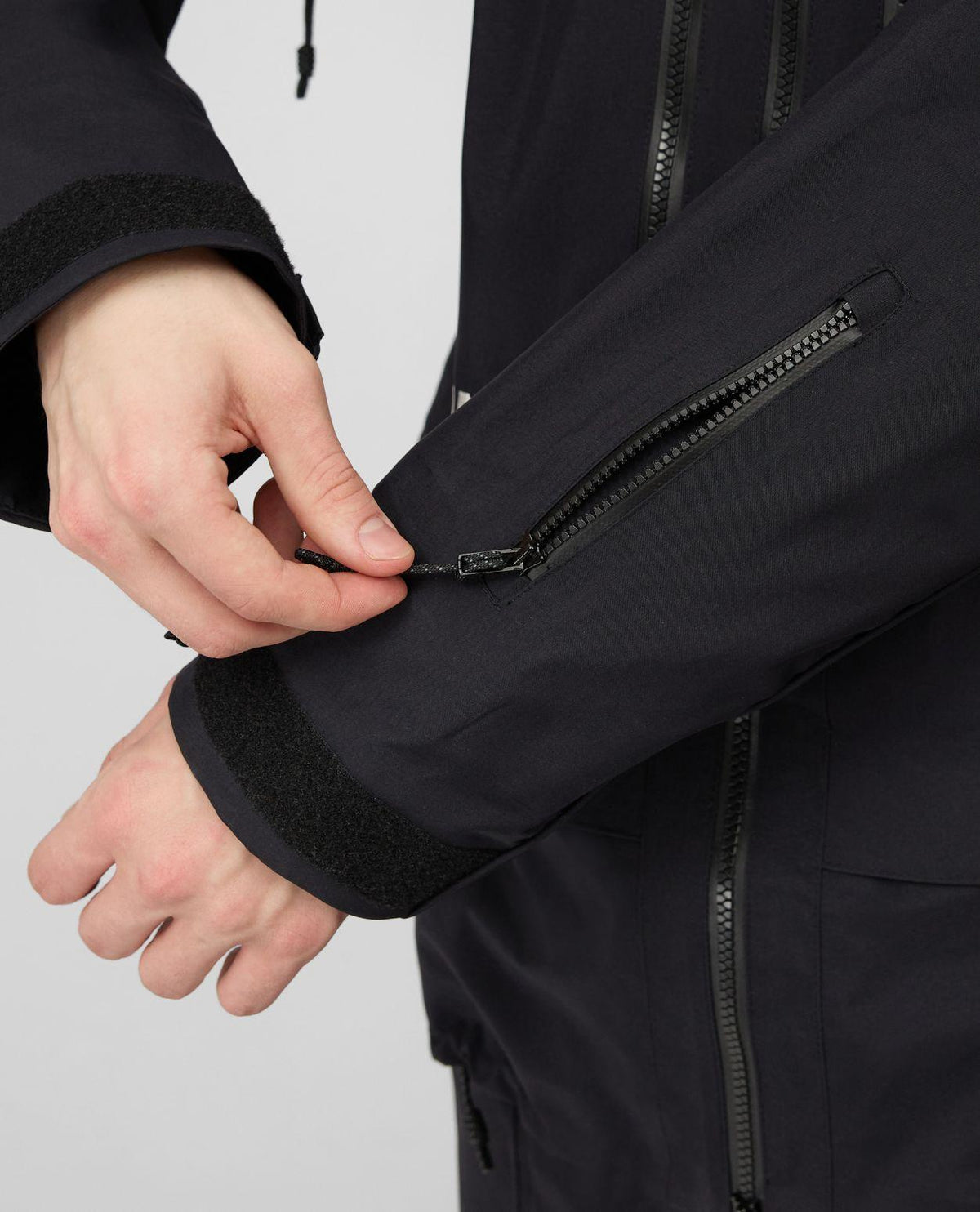 Närbild på ärmen och den slitstarka dragkedjan på Mammut Eiger Free Pro HS Hooded Jacket i svart.