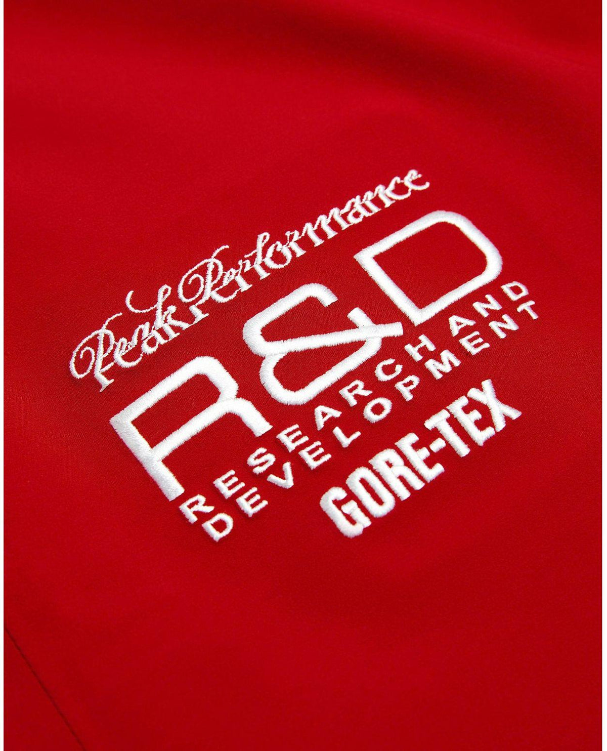 Detaljbild på broderade Peak Performance R&D och Gore-Tex-logotyper på rosa skidbyxor för dam.