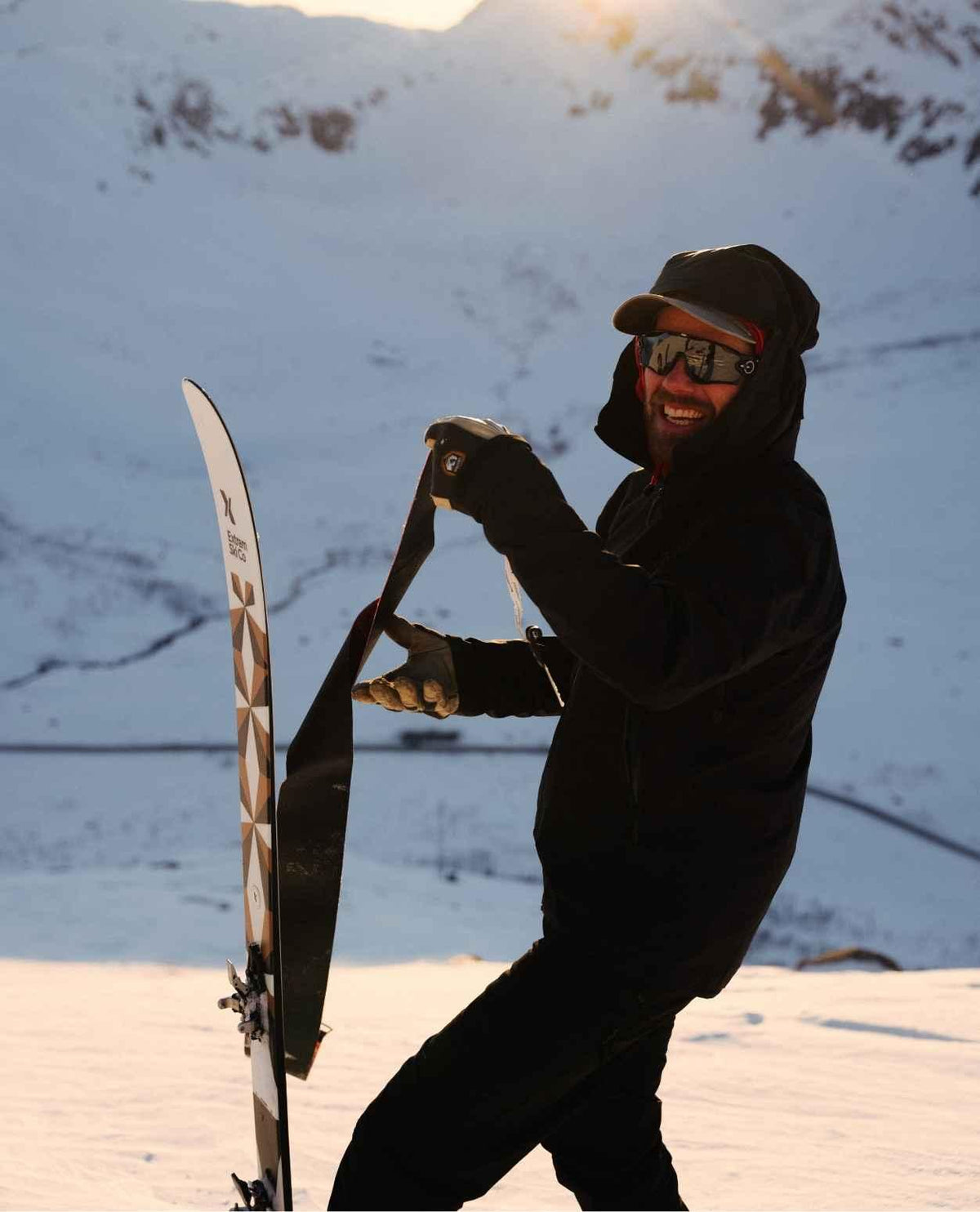 SkidÄkare i soligt alpint landskap som drar av stighudar frÄn en Extrem Ski Co Drifter 102 skida.
