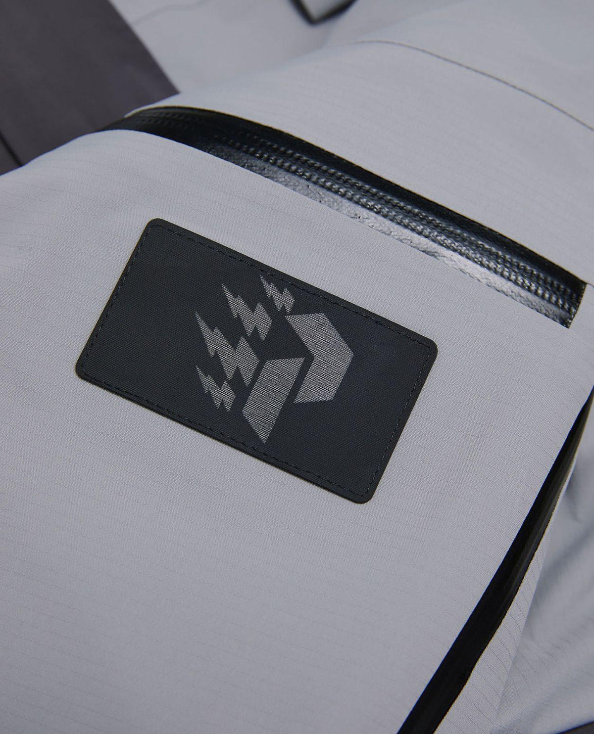 Peak Performance WeiTien Ridge Ace skidress i grått material med logotypdetalj och vattentät dragkedja.