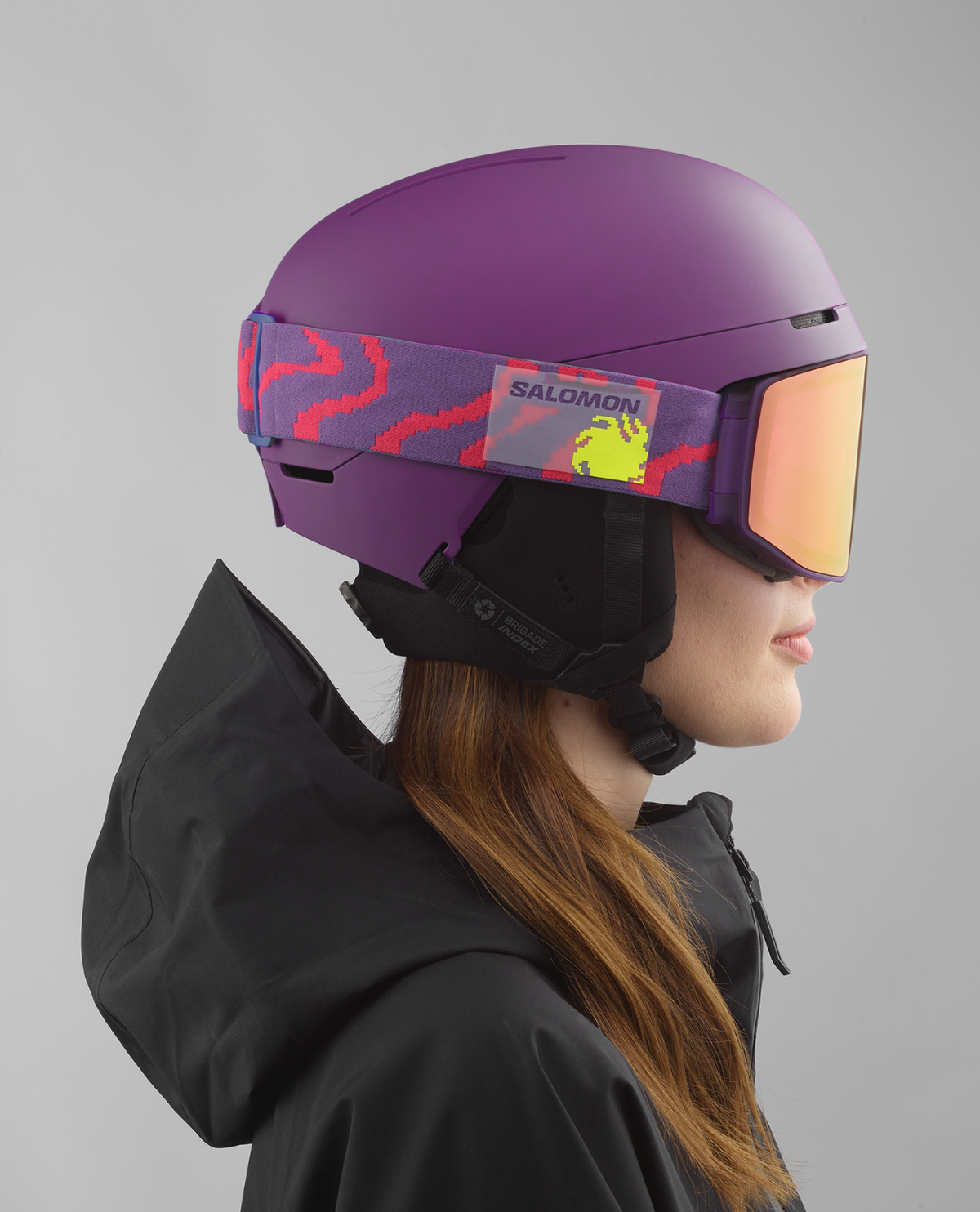 Salomon Brigade Index MIPS skidhjelm i lila färg med matchande skidglasögon på skidåkare.