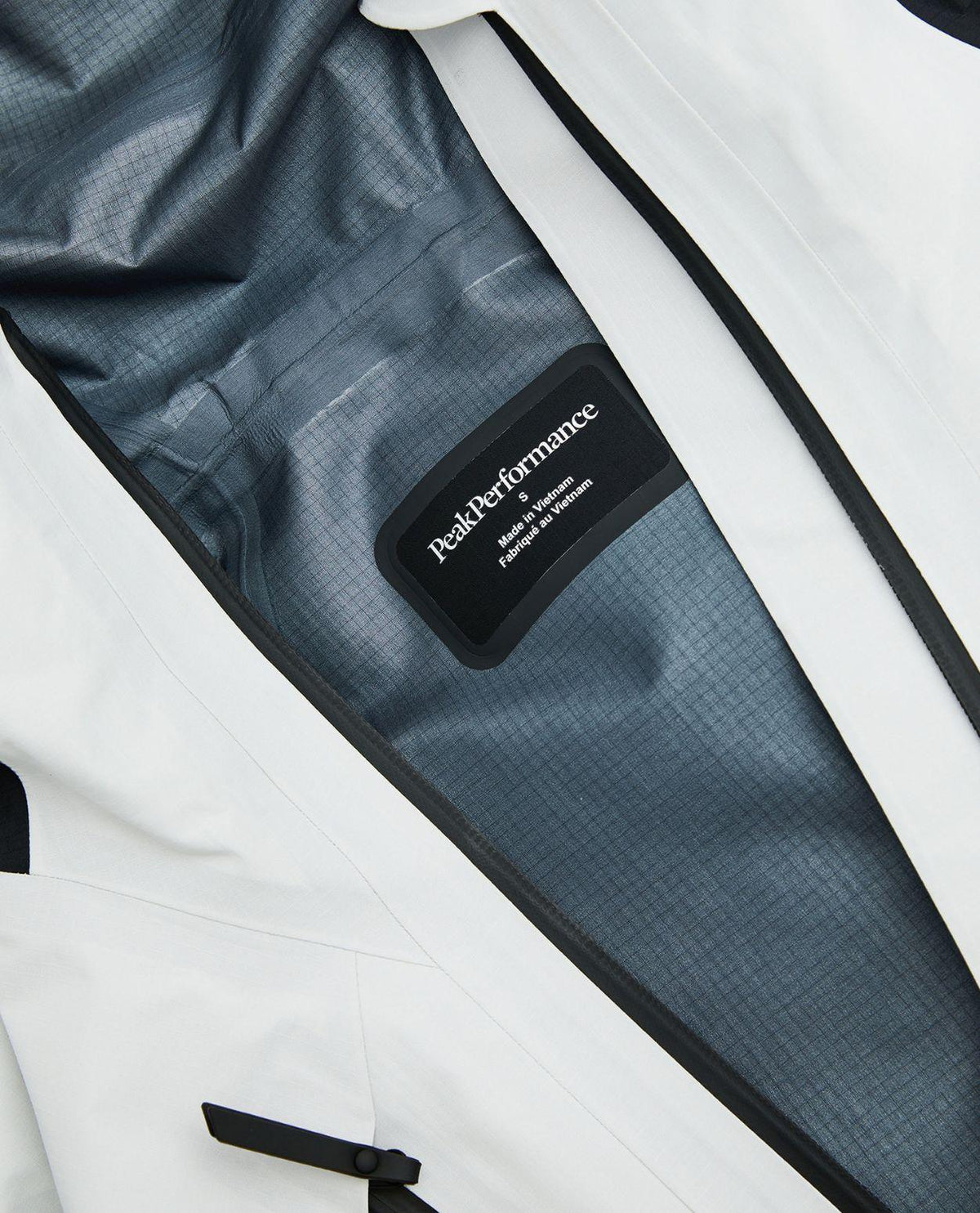 Närbild på insidan och logotypen i Peak Performance Vertical Gore-Tex Pro Jacket dam i vitt.