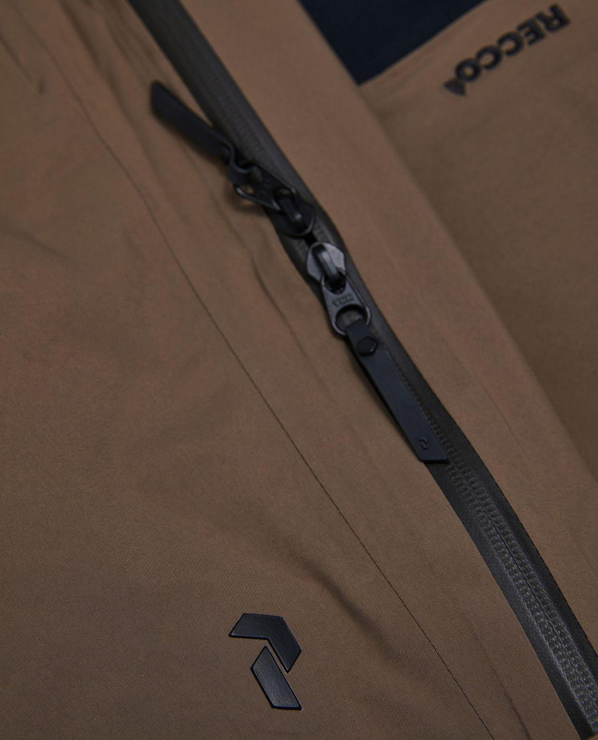 Detaljbild på vattentäta dragkedjor och Recco-reflektor på Peak Performance Alpine Gore-Tex Insulated Skidbyxor Dam Brun.