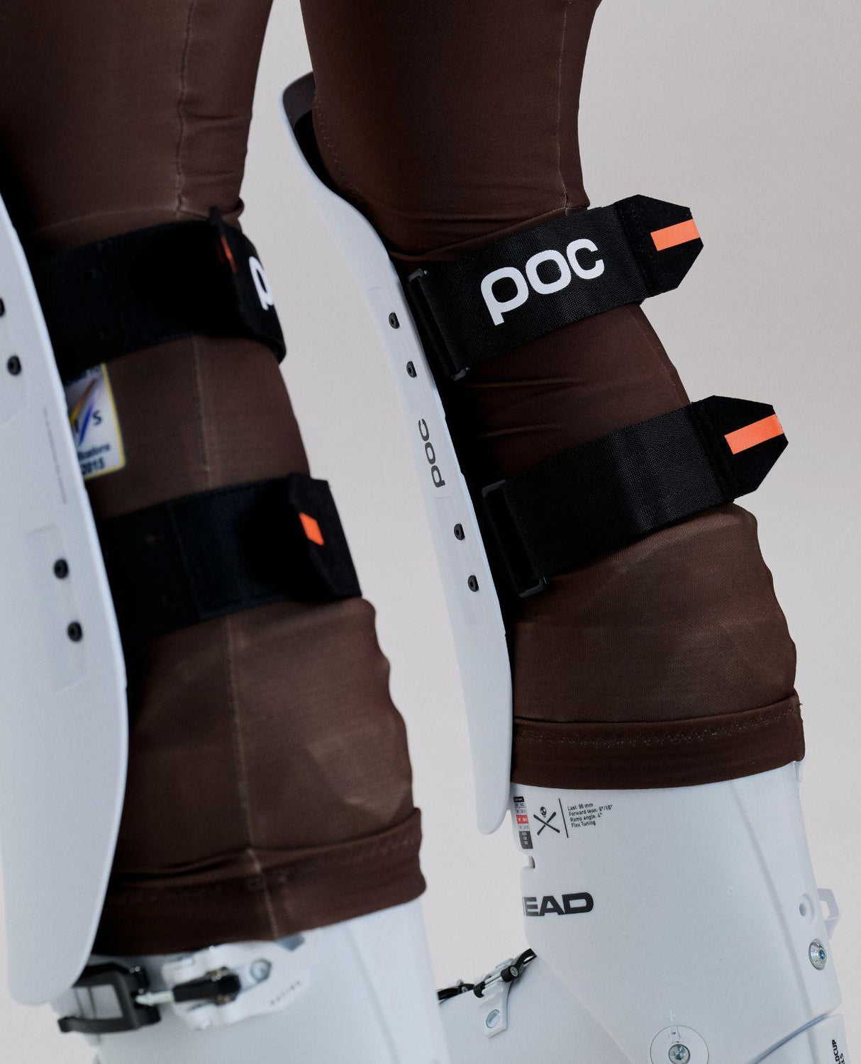 POC Shins Race benskydd i vitt på skidentusiastens ben tillsammans med pjäxor för alpin racing.