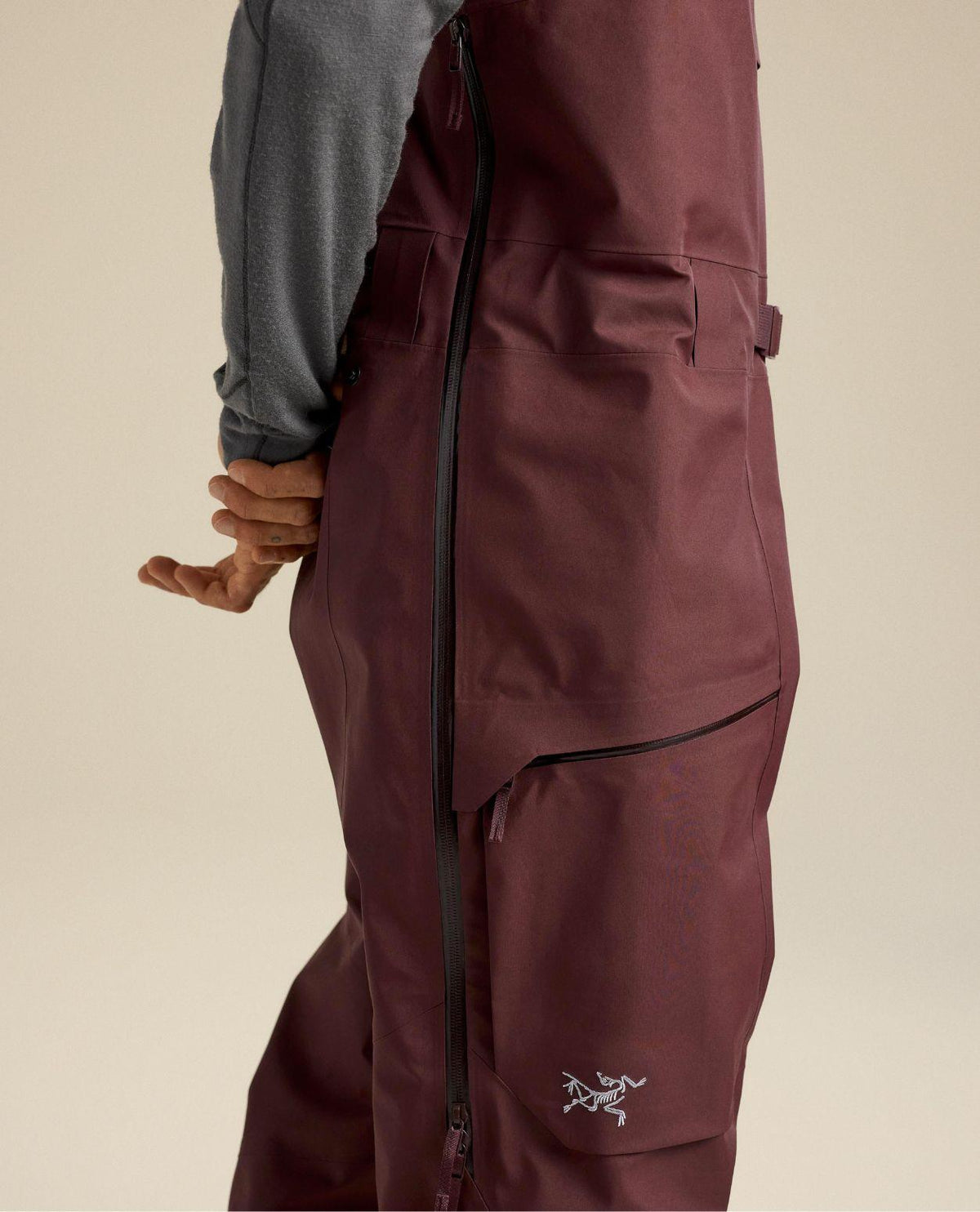 Arc'teryx Sabre Bib Men i lila färg med fokus på skidbyxans sidodragkedja och benficka.