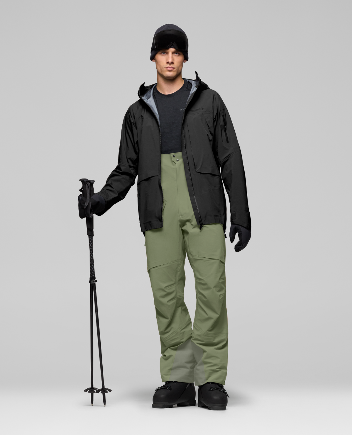 Norrøna Møre Gore-Tex Salopette Men i färg Deep Lichen Green med tillhörande skidutrustning.
