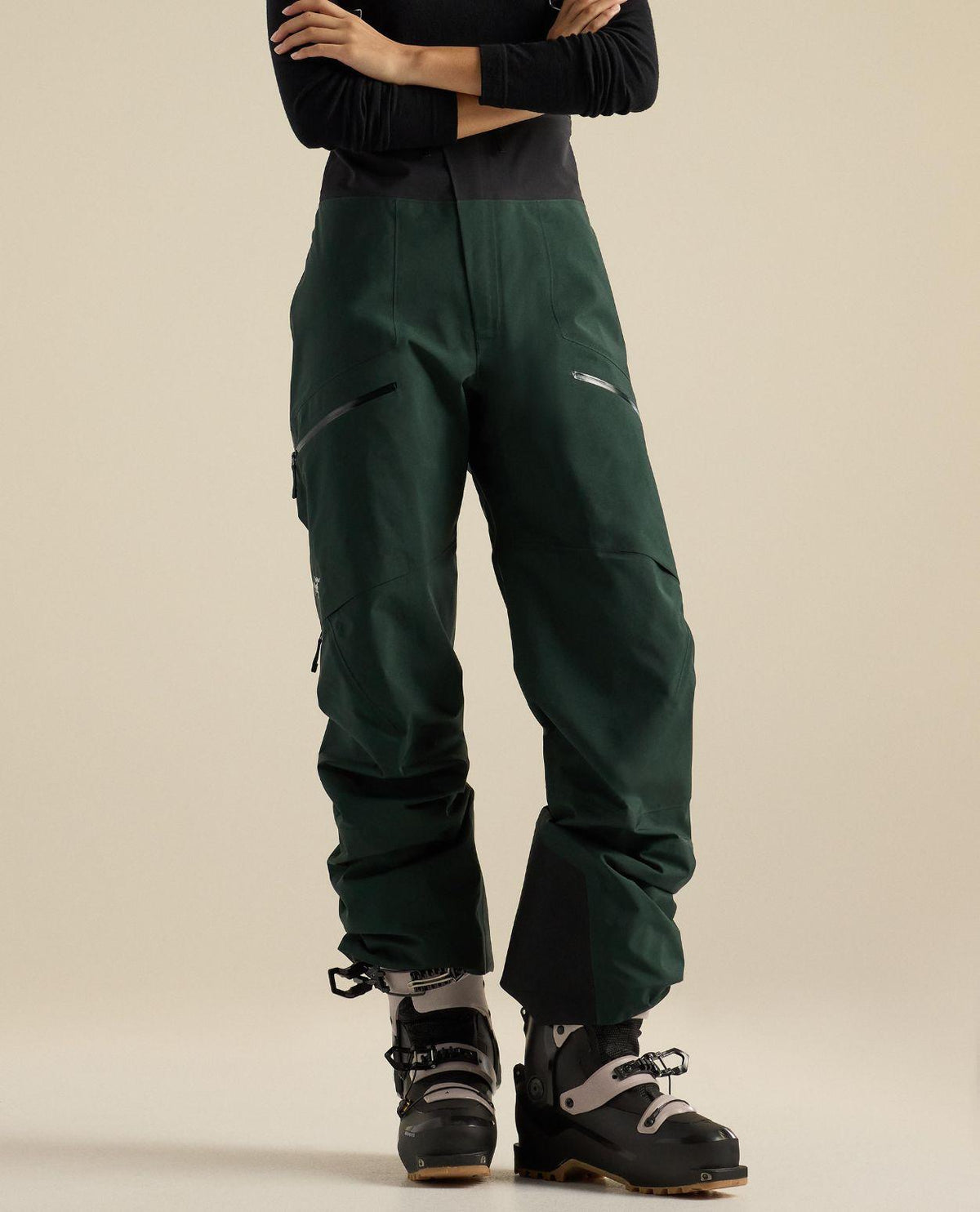 Arc'teryx Rush Bib Pant Women i mörkgrönt GORE-TEX Pro material på dammodell med skidpjäxor.