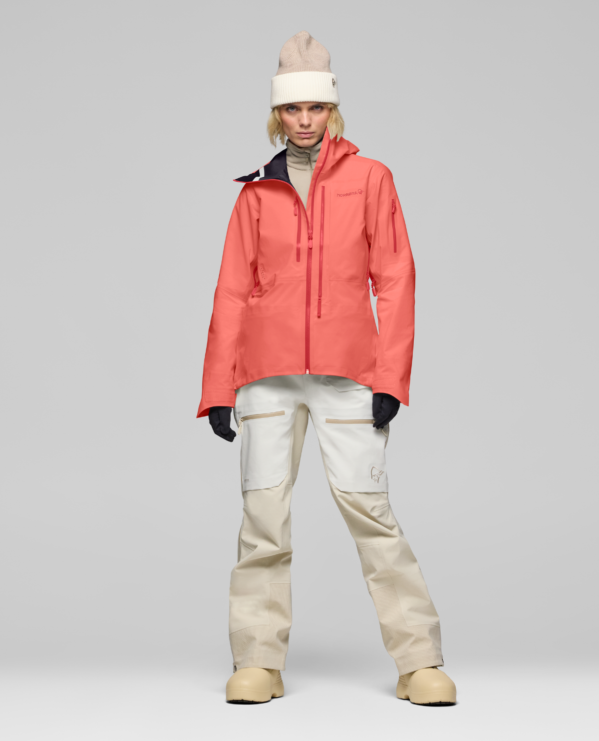 Norrøna Lofoten Gore-Tex Pro Jacket Dam i korallfärgat utförande med matchande skidbyxor och mössa.