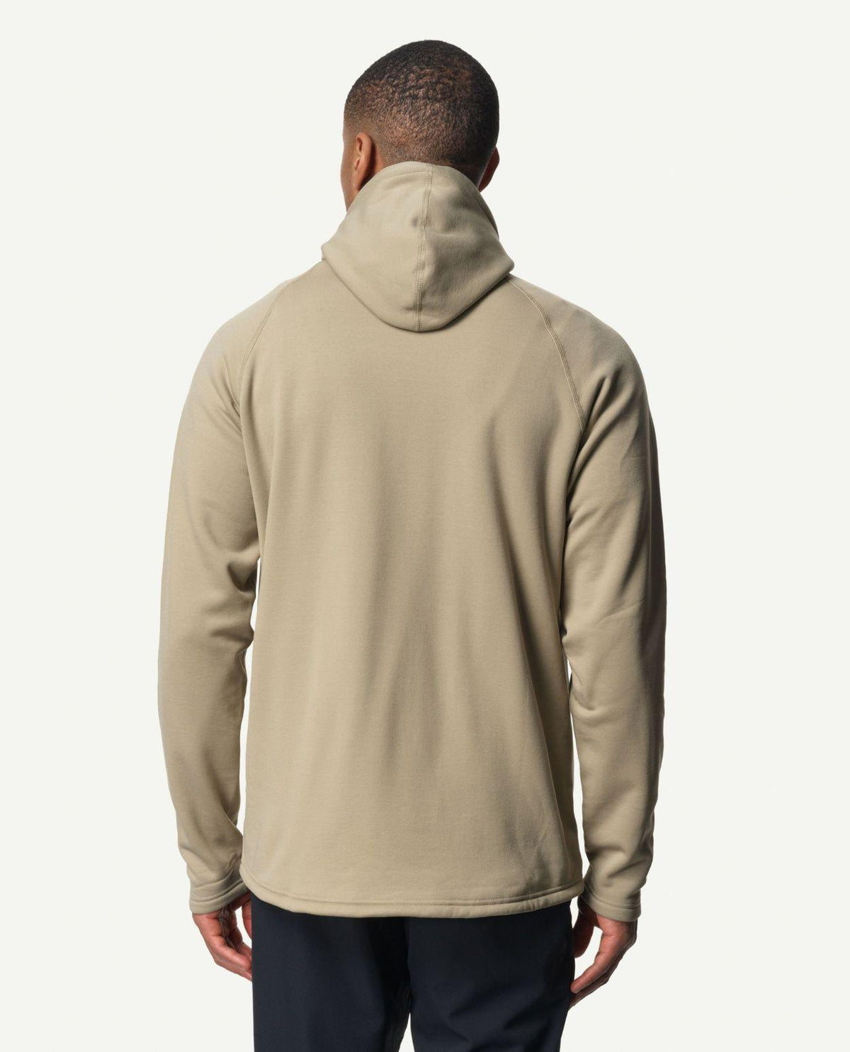 Man bakifrån iförd en grön hoodie från Houdini med huva och långa ärmar.