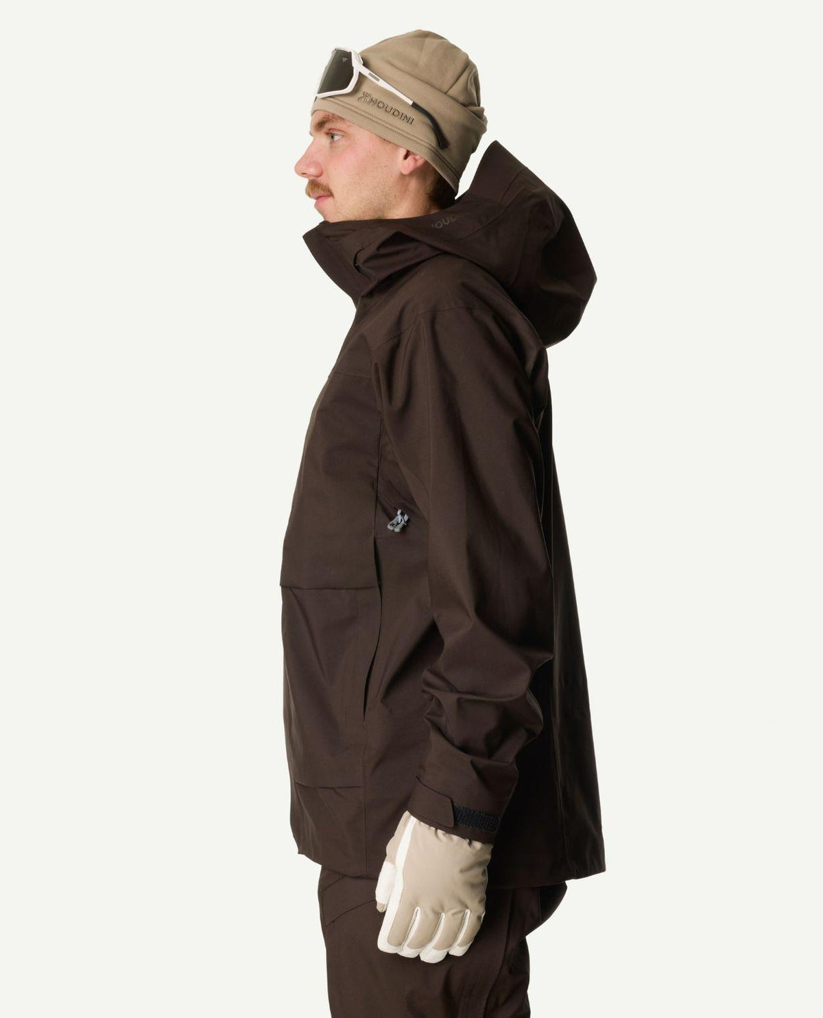 Man i profil iklädd bruna skidjackan Houdini Rollercoaster Jacket II med huva uppe.