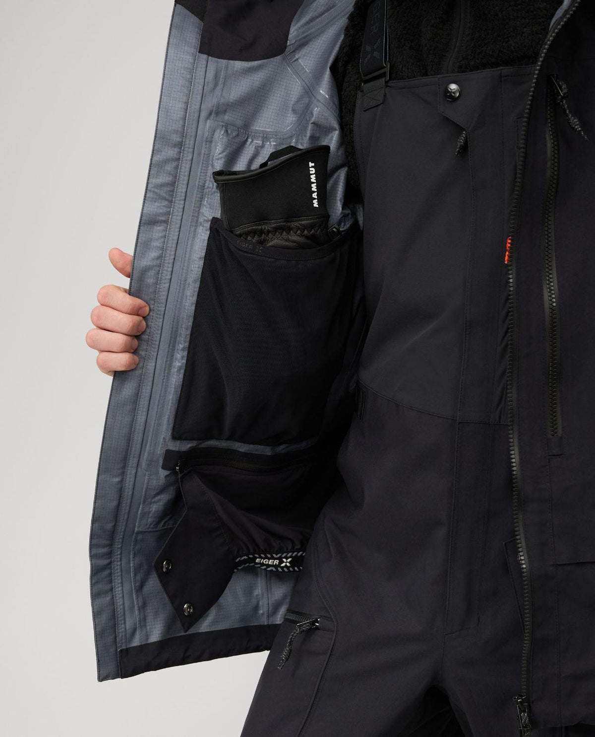 Mammut Eiger Free Pro HS Hooded Jacket i svart, närbild på insidans praktiska innerfickor och snölås.