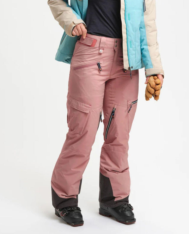 Elevenate Lavancher Cargo Pants Dam i mörkrosa färg, burna tillsammans med skidjacka och pjäxor.