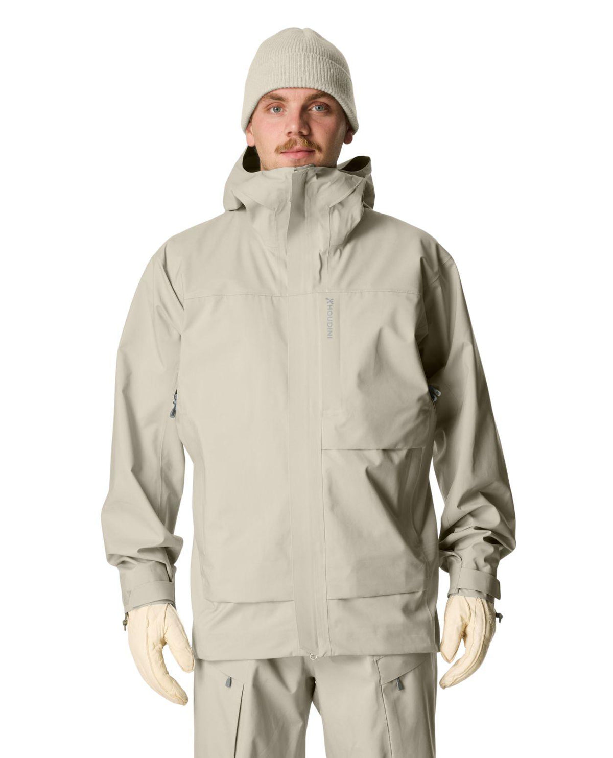 Manlig skidåkare iförd grön-grå Houdini Rollercoaster Jacket II och matchande mössa.