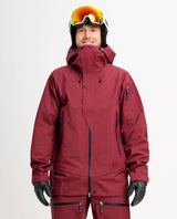 Elevenate Pure Jacket Men i färgen Tibetan Red på en manlig skidåkare iförd hjälm och skidglasögon.