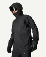 Skidåkare i profil bärandes en svart Houdini Rollercoaster Jacket II med huva uppdragen och skidglasögon.