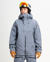 Manlig skidåkare iförd Elevenate Pure Jacket i blått med matchande skidkläder, hjälm och skidglasögon.