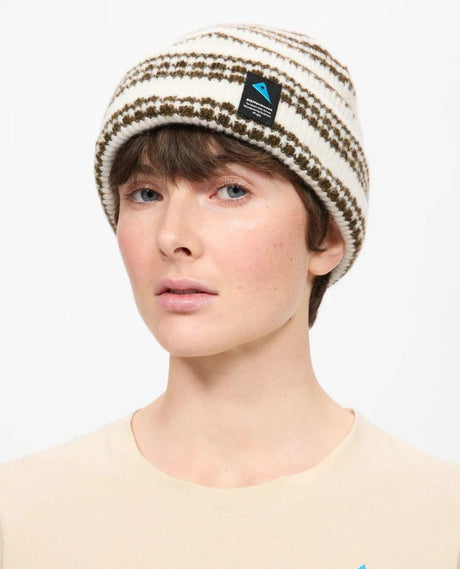 Klättermusen Runa Bandr Beanie i snövitt utförande med uppvikt kant och mönstrad stickning, buren av en person.