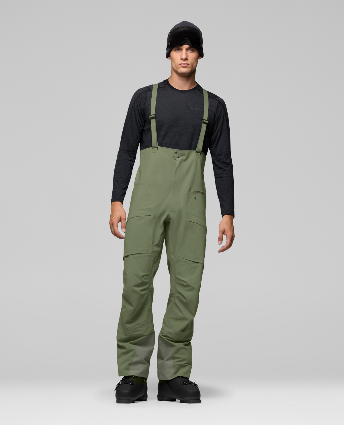 Norrøna Møre Gore-Tex Salopette Men i färg deep lichen green på modell i skidutrustning.