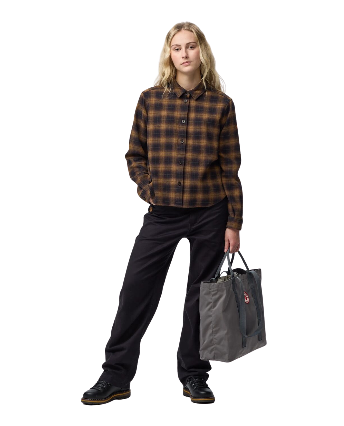 Kvinna som bär Fjällräven Övik Boxy Flannel Shirt Women i svart och brun flanell tillsammans med svarta byxor och väska.