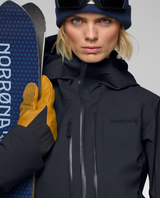 Norrøna Lofoten Gore-Tex Pro Jacket Dam - Caviar Black med skidor och gula handskar