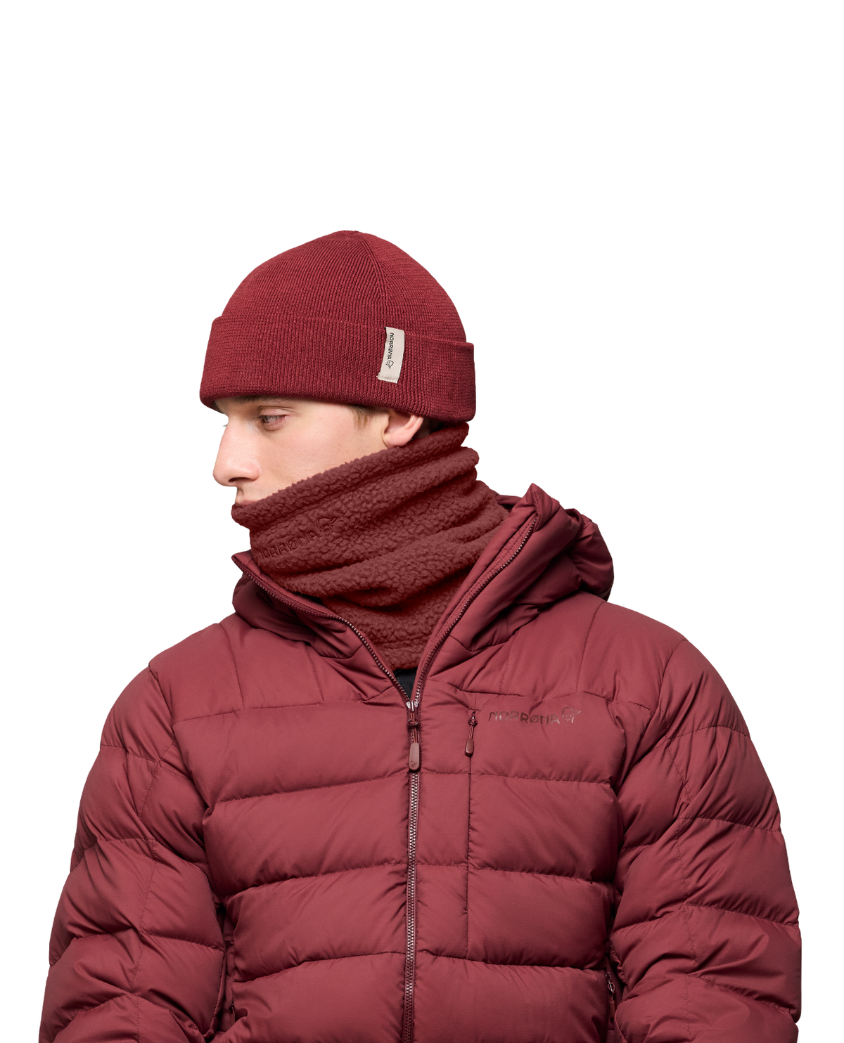 Norrøna /29 warm3 Neck i vinrött på modell som bär matchande mössa och dunjacka.
