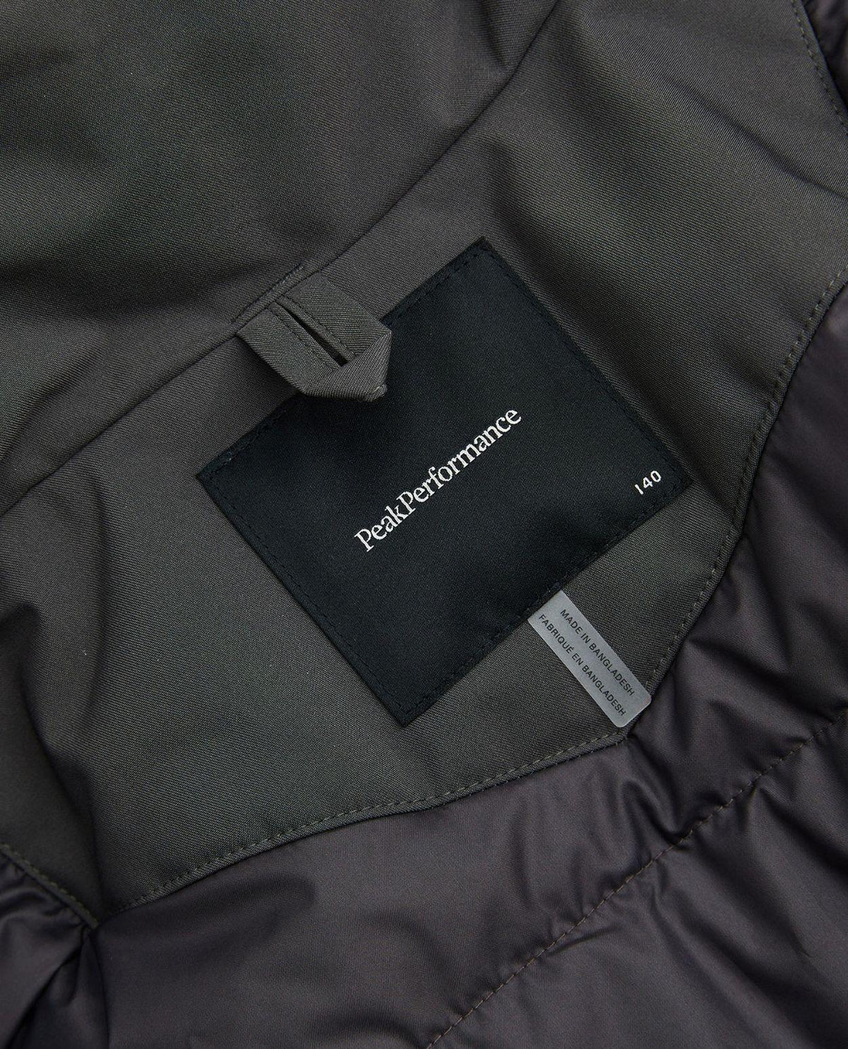 Närbild på inneretikett och logotyp i nacken på Peak Performance Gravity Insulated Jacket Junior.