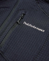 Närbild på bröstpartiet av Peak Performance Trail Polartec Zip Hood i svart med broderad logotyp och dragkedja.
