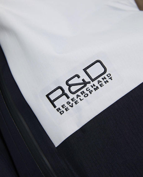 Närbild på broderad R&D-logotyp på Peak Performance skidbyxor i modell Vertical Gore-Tex Pro Bib Pants för herrar.