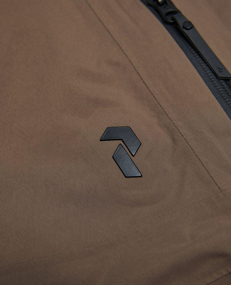 Närbild på Peak Performance-logotypen på bruna skidbyxor i Gore-Tex.