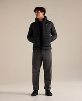 Man i svart Arc'teryx Cerium Hoody dunjacka med huva och händerna i fickorna.