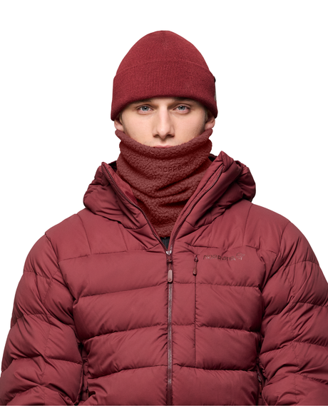 Norrøna /29 warm3 Neck i vinrött buren av modell med matchande mössa och dunjacka.