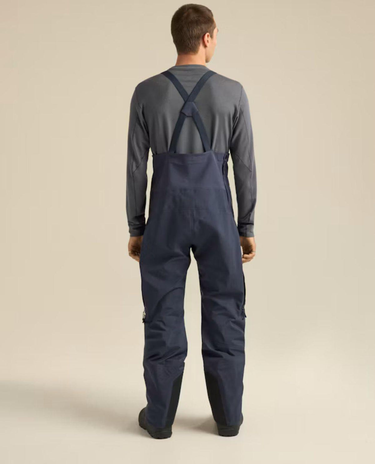 Man bakifrån iförd Arc'teryx Rush Bib skidbyxor i färgen Black Sapphire.
