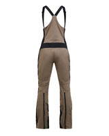 Peak Performance Stretch Bib Pants Women i Terrain Tan och Black visas bakifrån med svarta hängslen och dragkedjor.