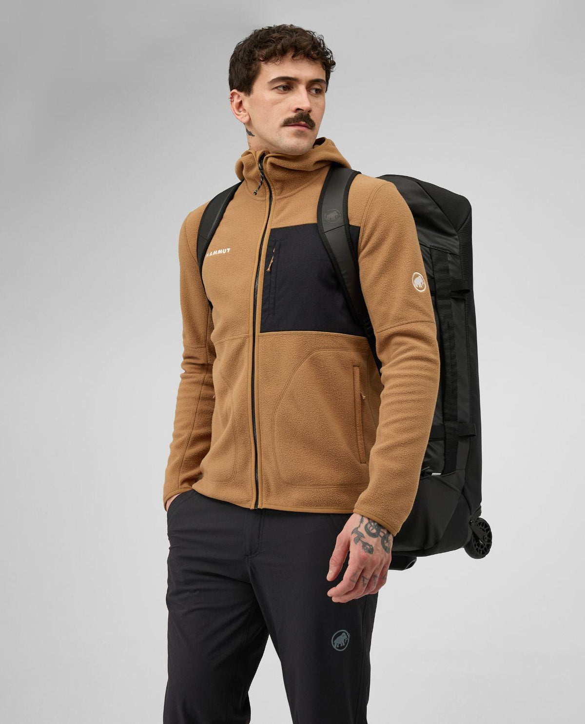 Man som bär den svarta resväskan Mammut Wheeled Cargo 90 som ryggsäck.