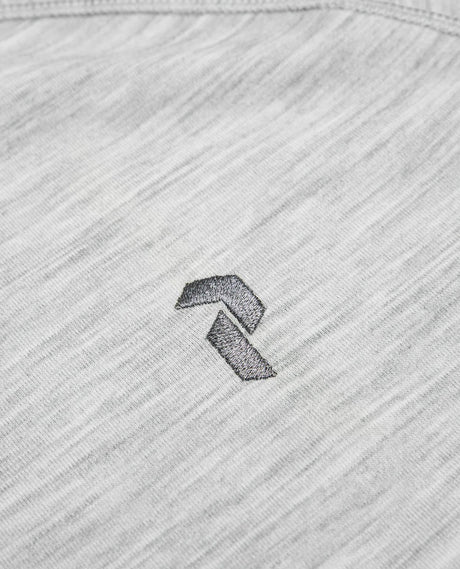 Närbild på det gråmelerade tyget med en broderad Peak Performance-logotyp.