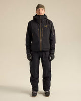 En person iklädd svarta Arc'teryx skidbyxor och matchande skidjacka framifrån.