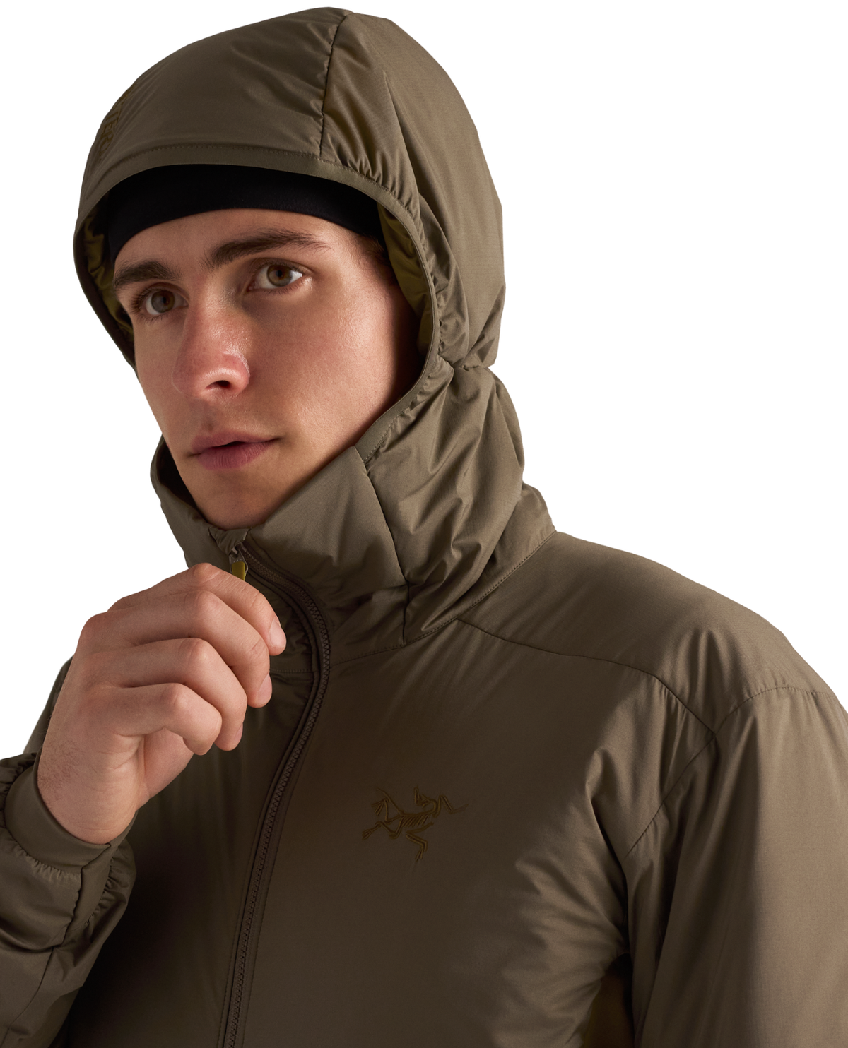 Man i olivfärgad Arc'teryx Atom Hoody mellanlager med huva och uppdragen dragkedja.