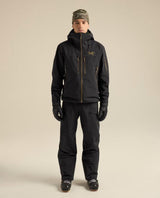 Man i skidkläder inklusive Arc'teryx Rush Jacket Men i svart med guldfärgade detaljer