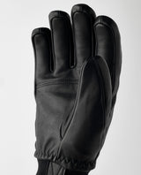 Hestra Omni 5 Finger skidhandske i svart nötnappa, visad från handflatan mot en ljus bakgrund.