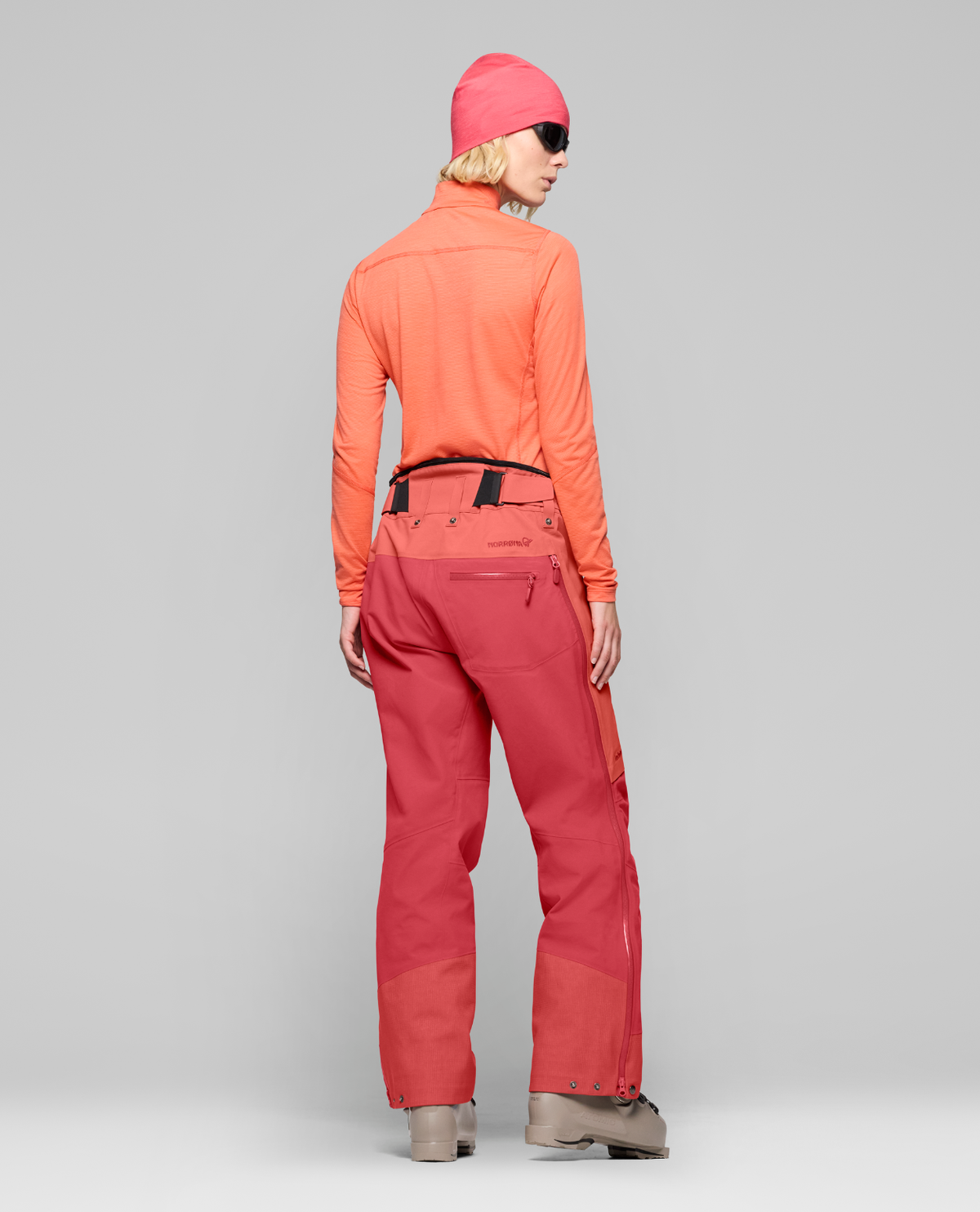 Norrøna Lofoten Gore-Tex Pro Pants Women i färgen Deep Sea Coral och Baked Apple, visad bakifrån på skidåkare.