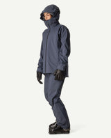 Kvinna iklädd Houdini Ride Jacket II i blått med matchande byxor, skidhandskar och pjäxor.