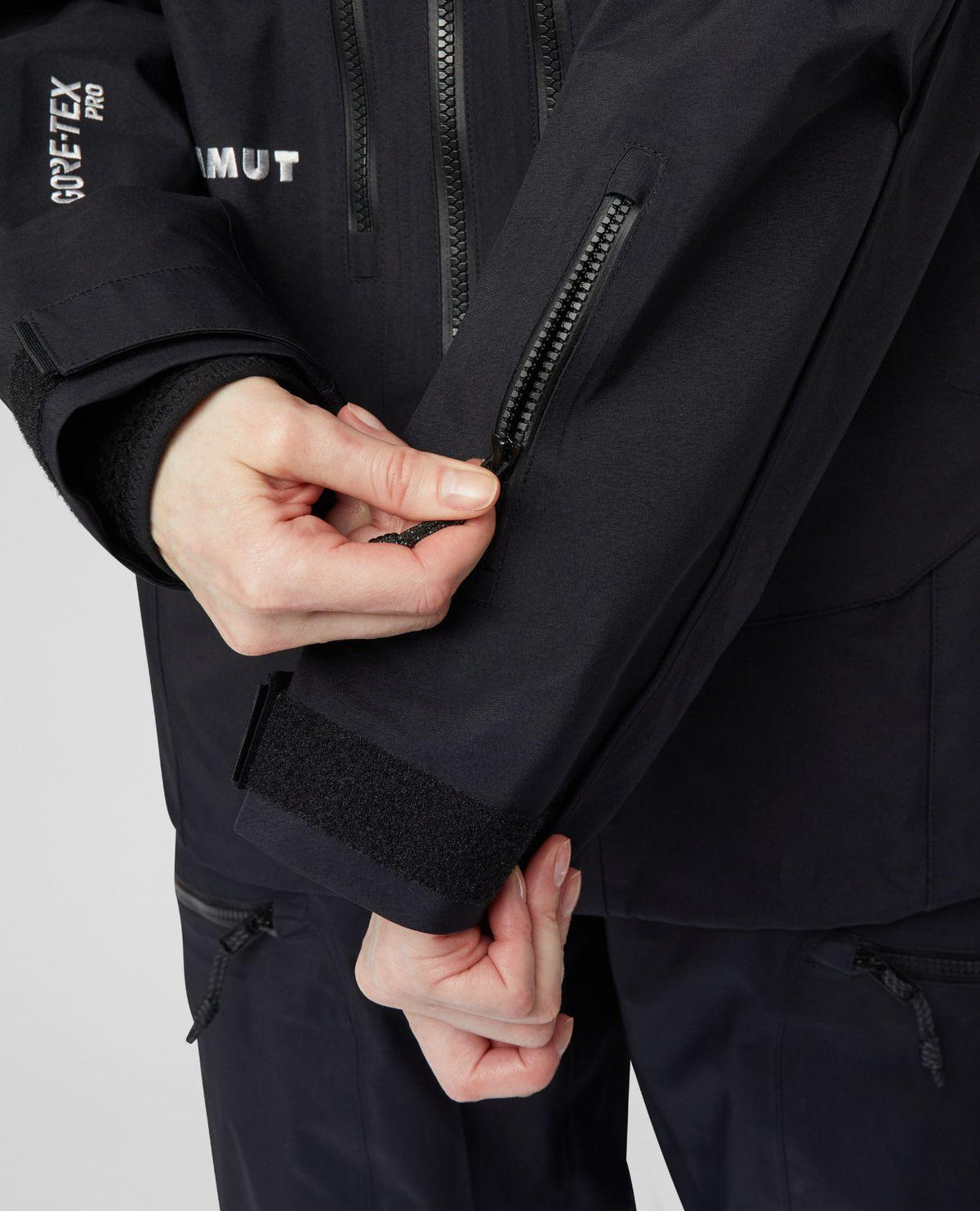 Detaljbild på Mammut Eiger Free Pro HS Hooded Jacket Women i svart, med fokus på dragkedja och ärmslut.
