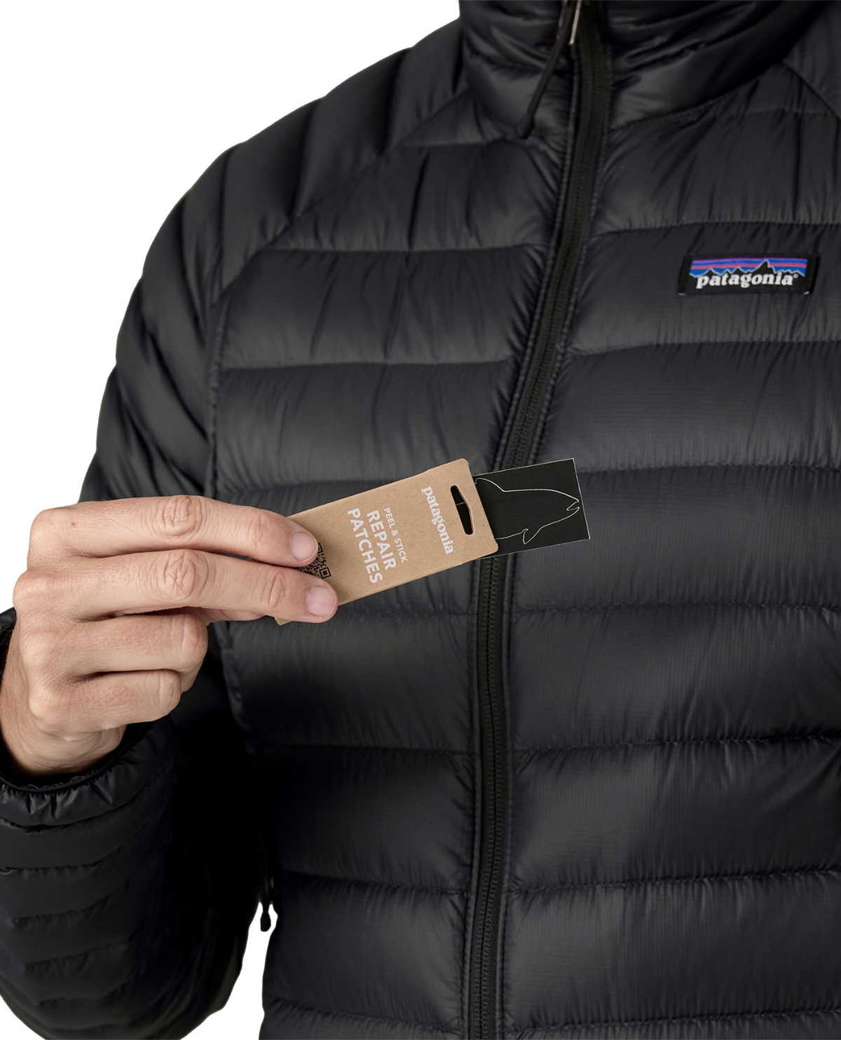 Närbild på person som håller i lagningslappar framför svarta dunjackan Patagonia Down Sweater Women