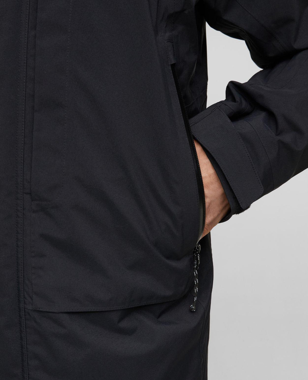 Närbild på ficka och dragkedja på Mammut Haldigrat Gore-Tex HS Thermo Hooded Jacket för herrar i svart färg.