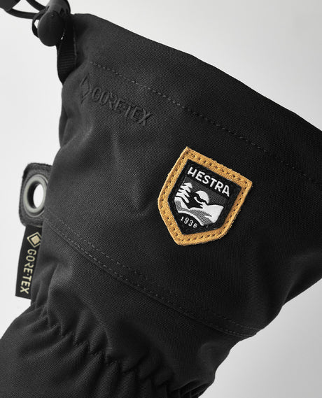 Närbild på en svart Hestra Army Leather Gore-Tex Mitt som visar Hestra-loggan och Gore-Tex-märkningen.